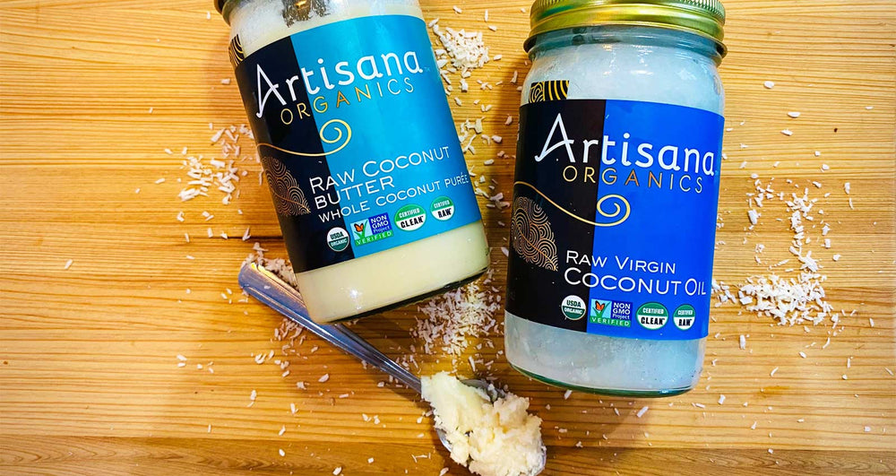A spoon with coconut butter on it in front of two jars.